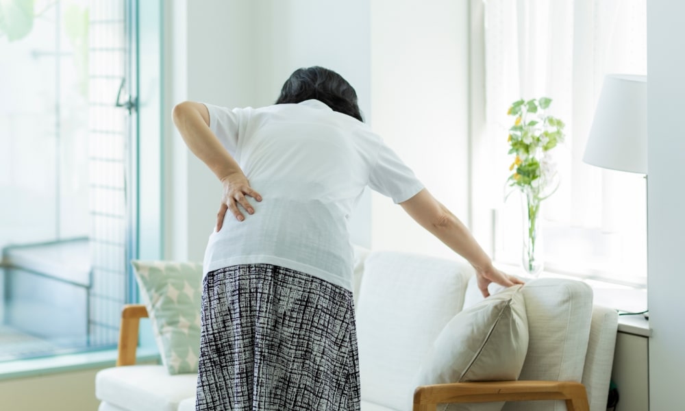 中腰でぎっくり腰の女性